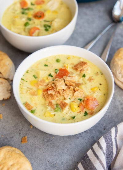 A bowl of chicken pot pie soup with carrots, chicken, corn, and topped with pie crust pieces.