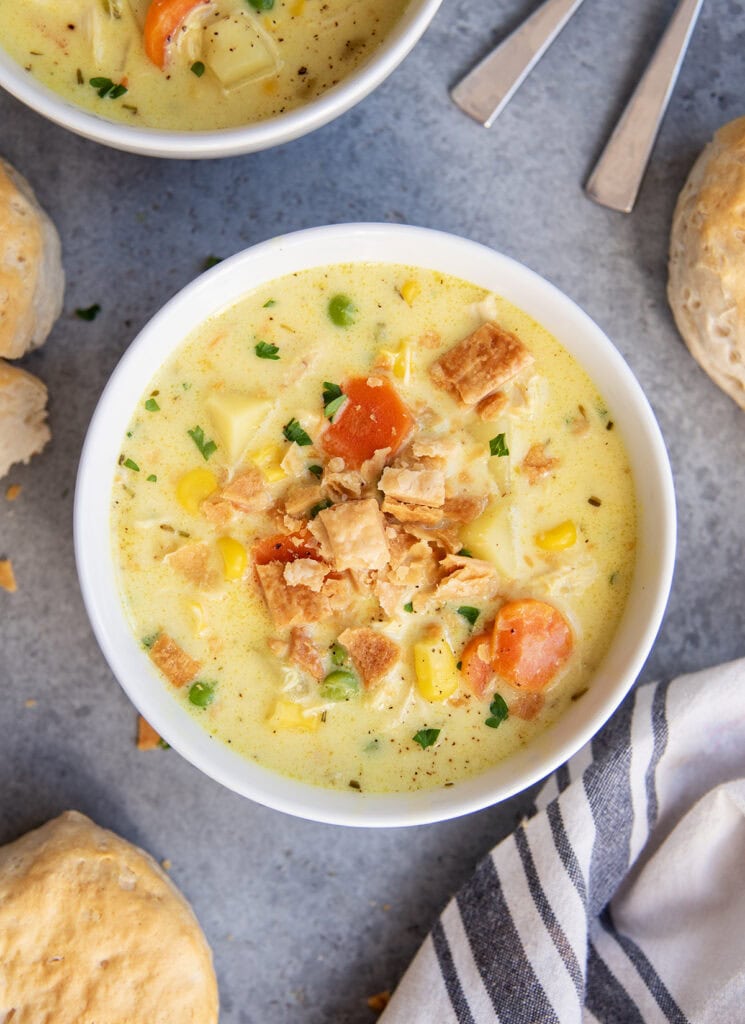A bowl of chicken pot pie soup with carrots, chicken, corn, and topped with pie crust pieces.