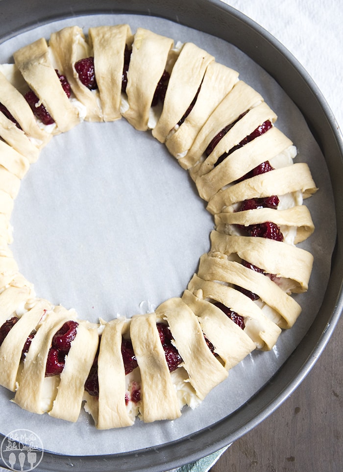 An unbaked raspberry cream cheese crescent ring on a round baking pan. 