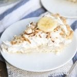 A slice of banana coconut cream pie topped with whipped cream and toasted coconut.