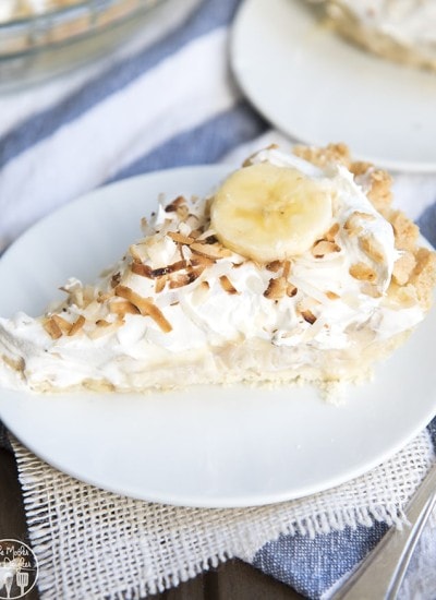 A slice of banana coconut cream pie topped with whipped cream and toasted coconut.