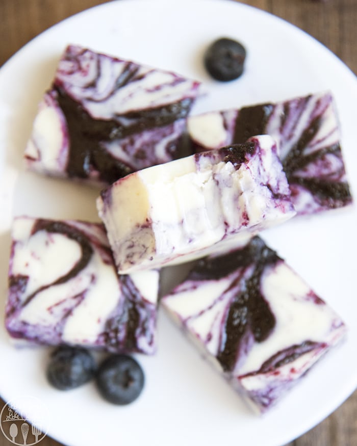 A pile of blueberry and white chocolate fudge on a white plate.