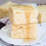 A stack of two pieces of corn bread topped with honey on a white plate