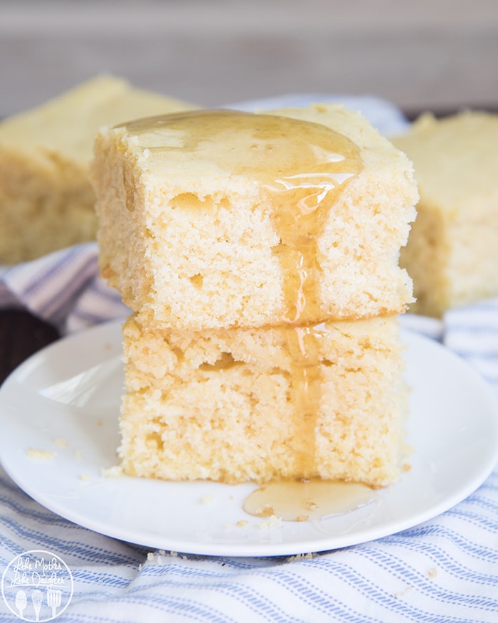 A stack of two pieces of corn bread topped with honey on a white plate