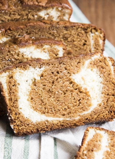 Slices of pumpkin swirled cream cheese bread laying against each other on a cloth.