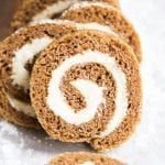 Pumpkin rolls swirled with cream cheese frosting stacked together.