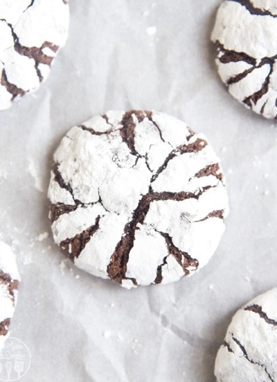 An overhead photo of chocolate crinkle cookies on a piece of parchment paper.