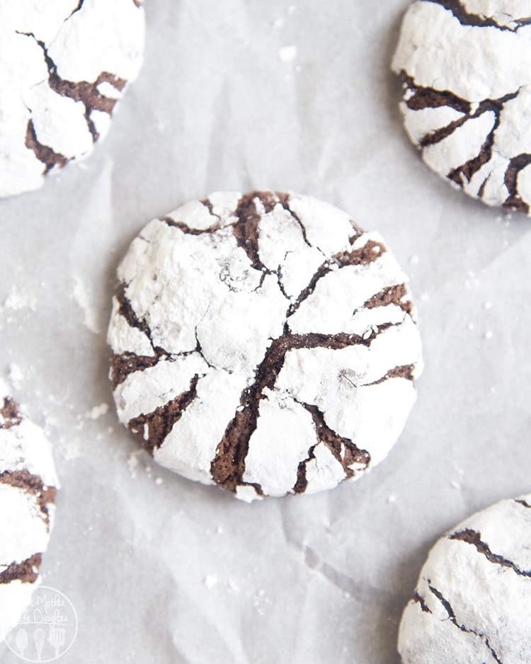 An overhead photo of chocolate crinkle cookies on a piece of parchment paper.