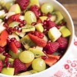 A bowl of fruit salad filled with only green and red fruits.