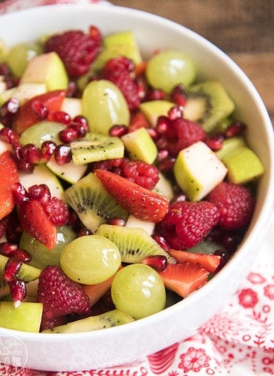 A bowl of fruit salad filled with only green and red fruits.