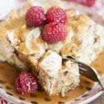 A plate of cinnamon roll french toast casserole topped with raspberries.