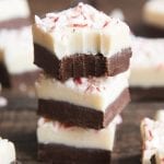 A stack of three pieces of peppermint bark fudge with a bite out of the top.