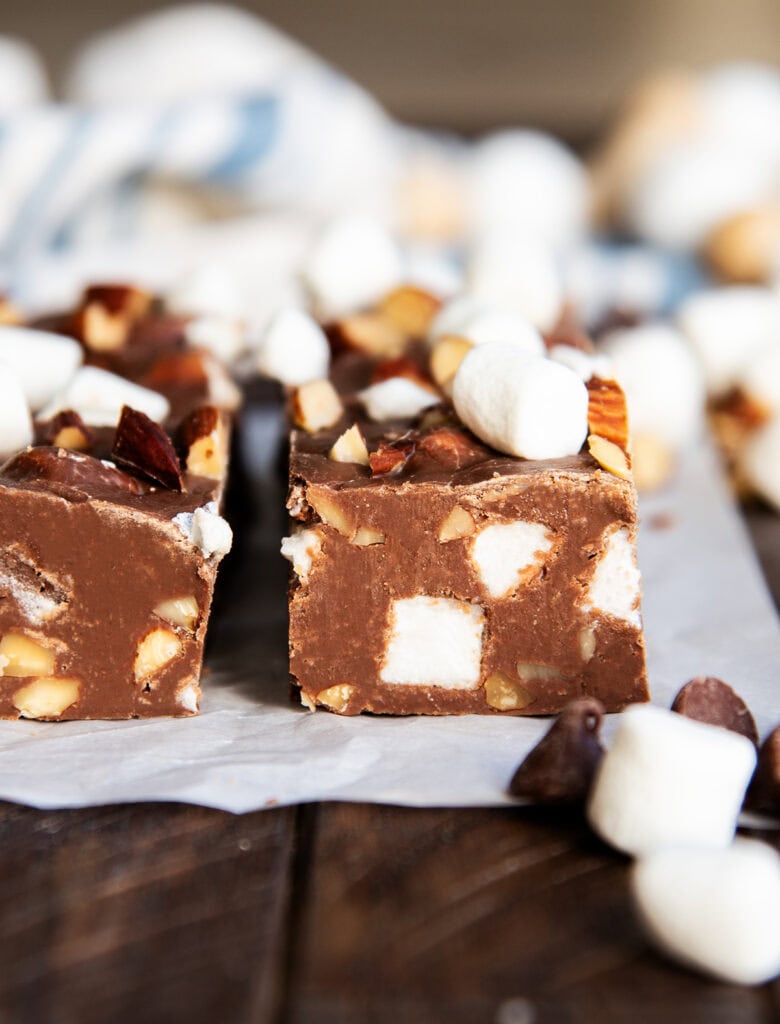 A side view of Rocky road fudge on parchment paper showing the almonds and mini marshmallows in the fudge piece.