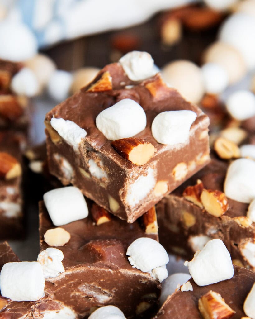 A pile of rocky road fudge, each piece is full of almonds and mini marshmallows.