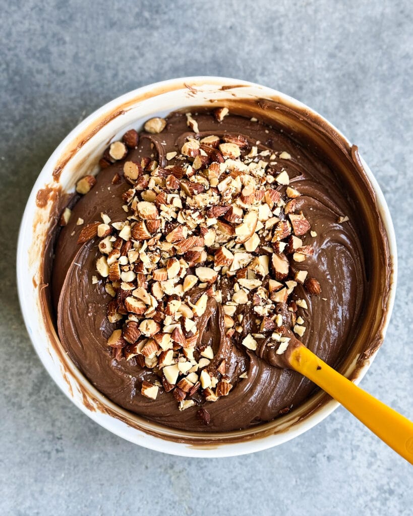 A bowl of microwave fudge with chopped almonds on top.