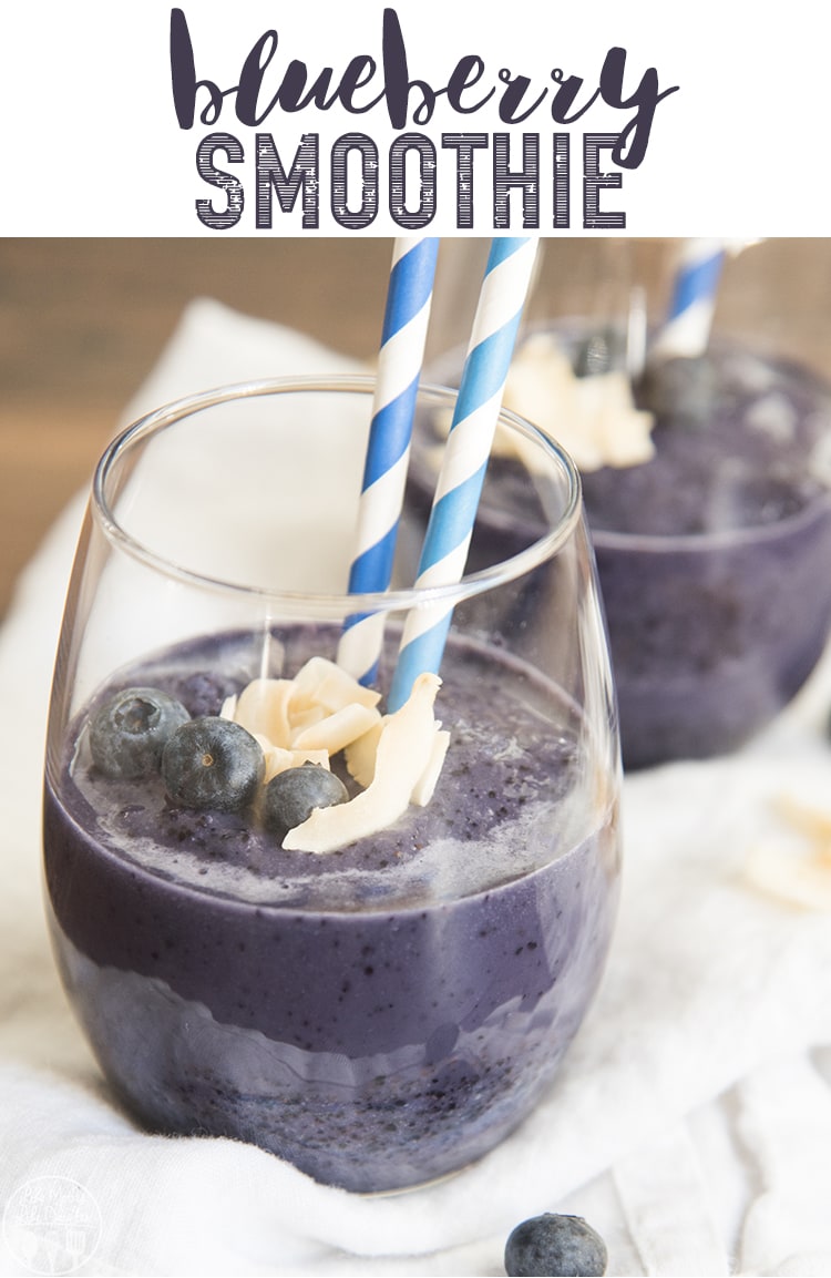 A blueberry smoothie in a glass with two blue straws in it.