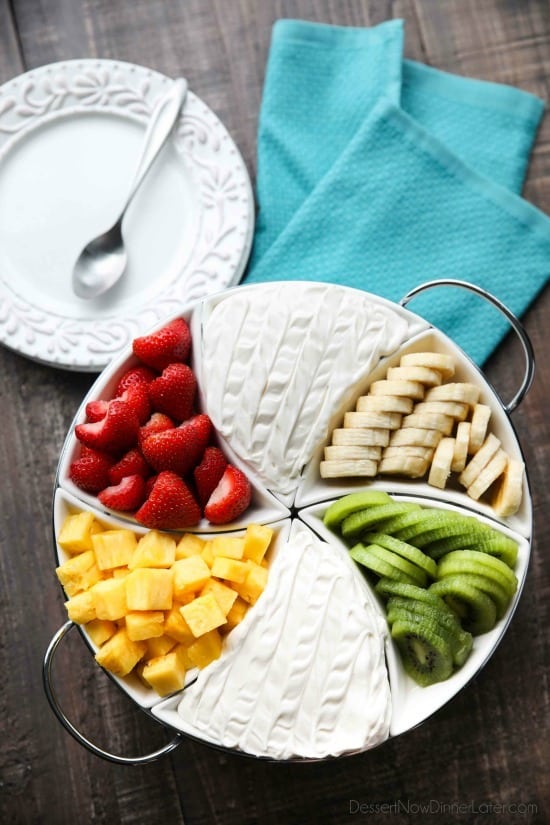 A coconut cream fruit dip in a tray arranged with fruit. 