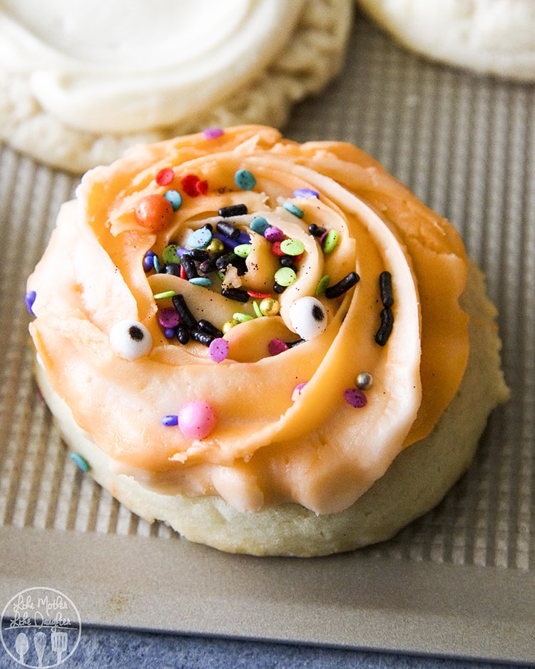 A sugar cookie topped with orange frosting and Halloween sprinkles.