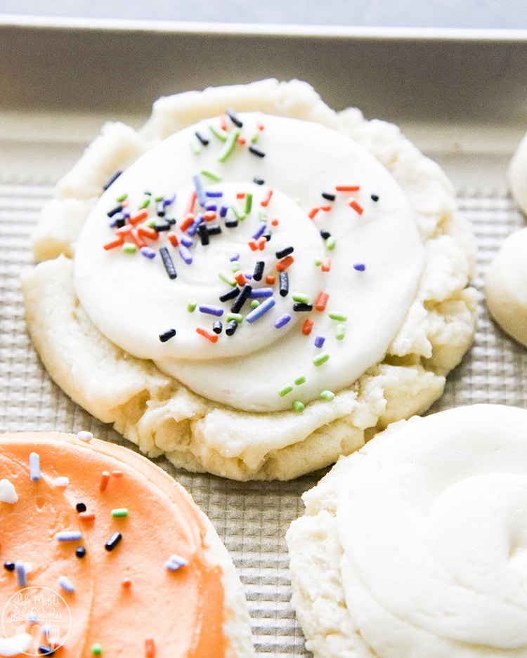 A sugar cookie topped with white frosting and sprinkles.