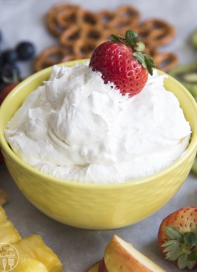 A bowl of pina colada fruit dip topped with a fresh strawberry.