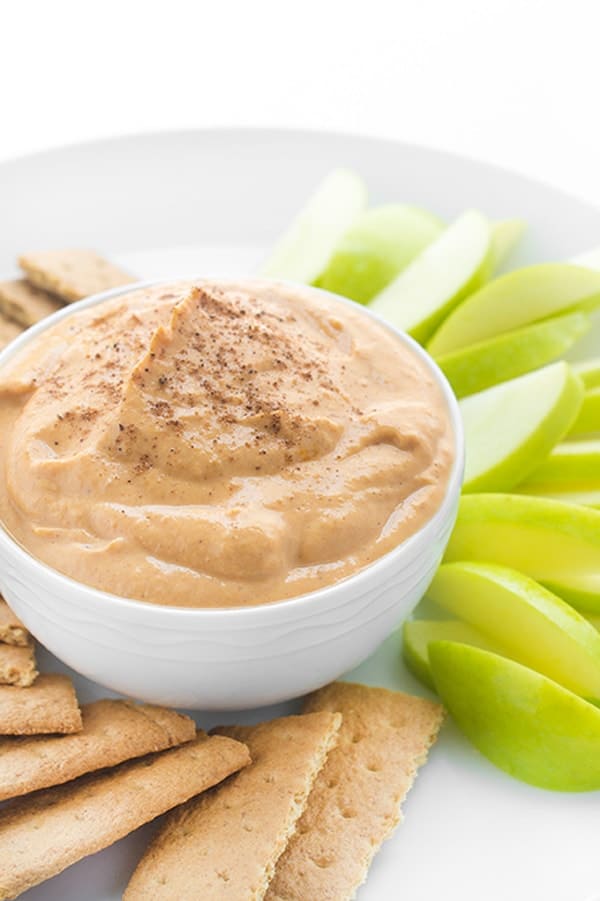 A pumpkin spice dip in a bowl with apples on the side. 