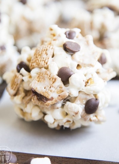 A smores popcorn ball with marshmallows, chocolate chips, and golden graham cereal.