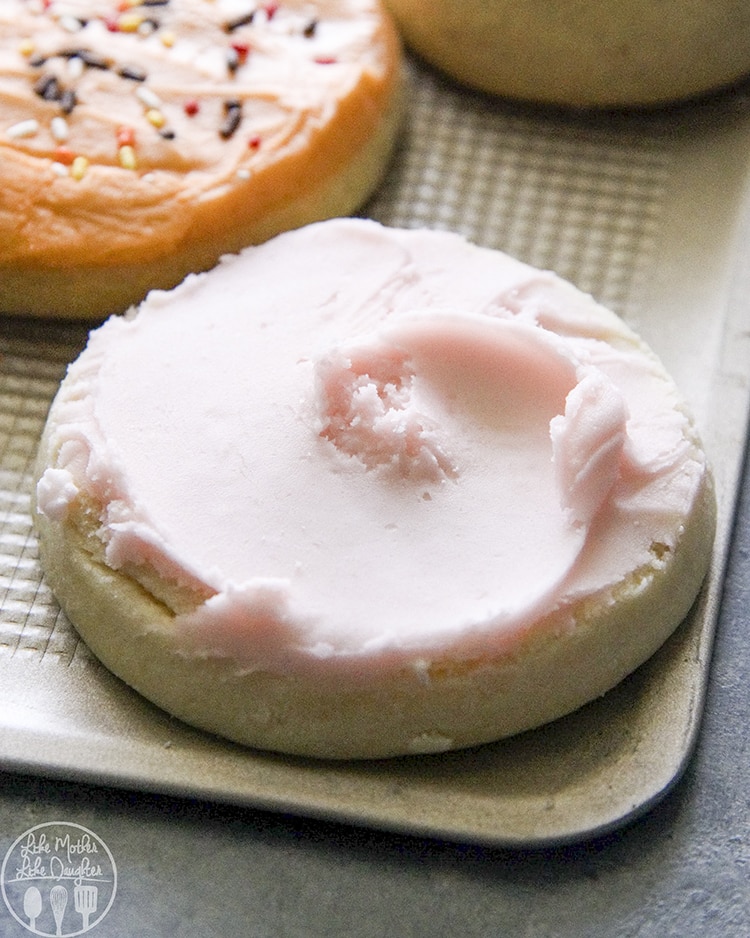A round sugar cookie topped with pink frosting.