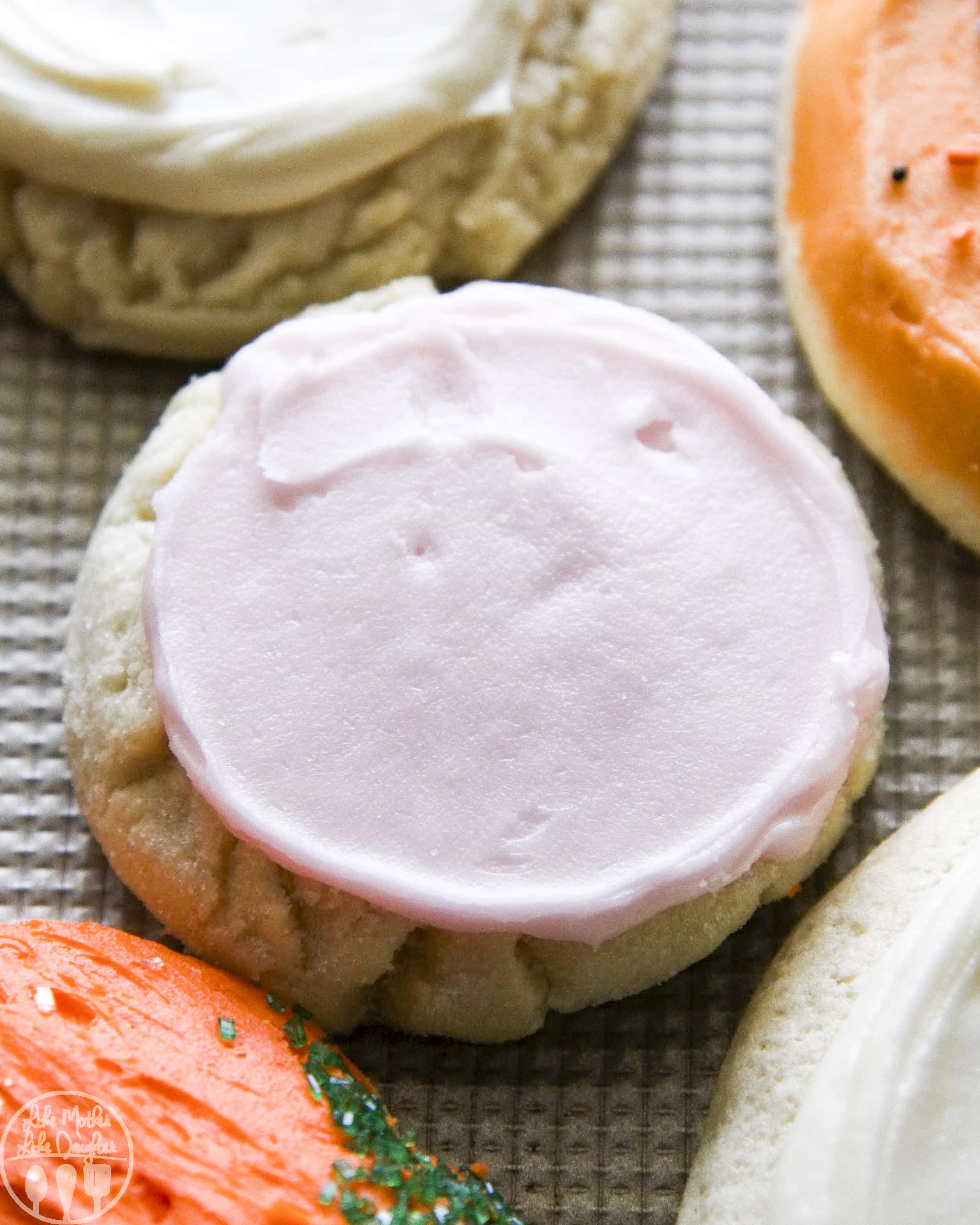 A sugar cookie with light pink frosting on top.