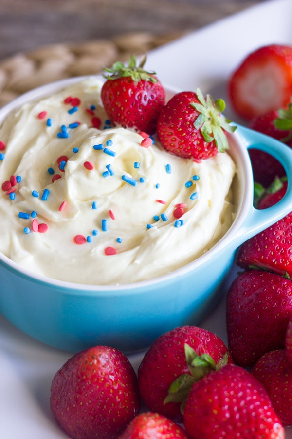 A vanilla pudding fruit dip topped with red and blue sprinkles. 