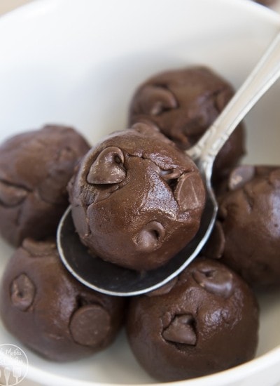 Close up image of chocolate cookie dough balls on a spoon in a white bowl.