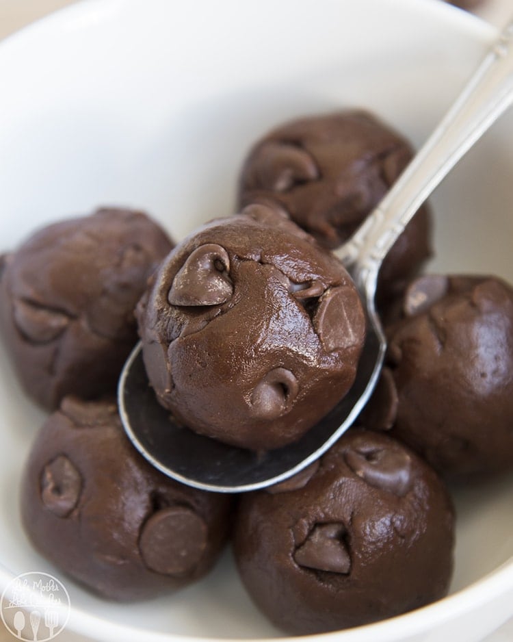 Close up image of chocolate cookie dough balls on a spoon in a white bowl.