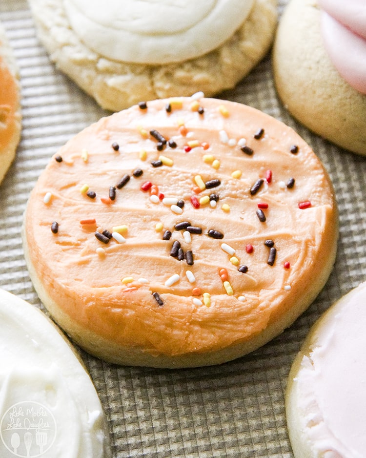 An orange frosted sugar cookie topped with sprinkles.