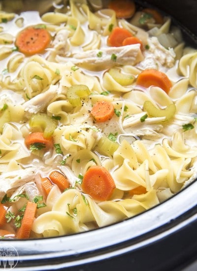 Close up image of slow cooker chicken noodle soup with noodles and ingredients visible.