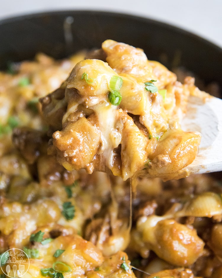 A spoonful of cheeseburger pasta, above a pot.