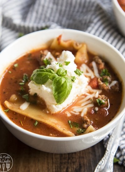 A bowl of lasagna soup topped with ricotta and fresh basil.