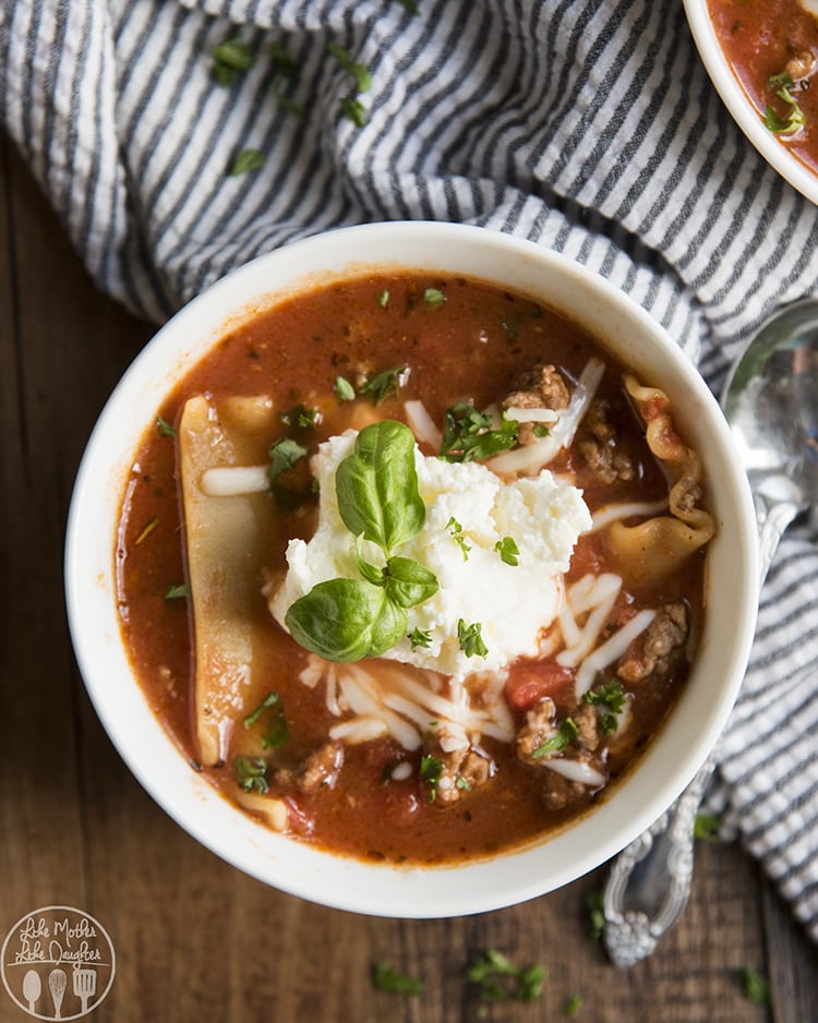 An overhead photo of a bowl of lasagna soup with a big pile of ricotta, and fresh basil on top.