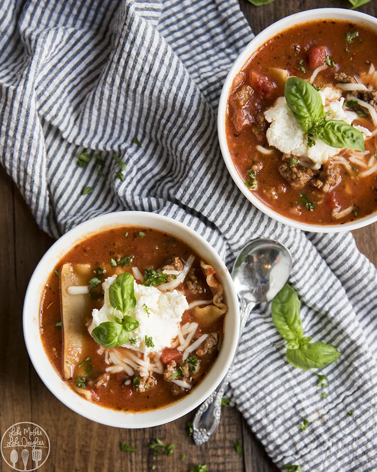 Two bowls of lasagna soup topped with basil leaves.
