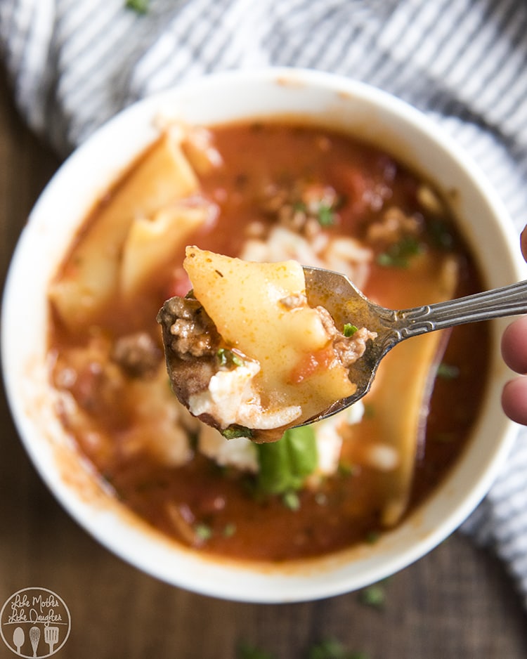 A spoonful of lasagna soup held above a bowl of the soup.