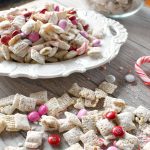Peppermint Puppy chow in a bowl with m&ms and candy cane pieces.