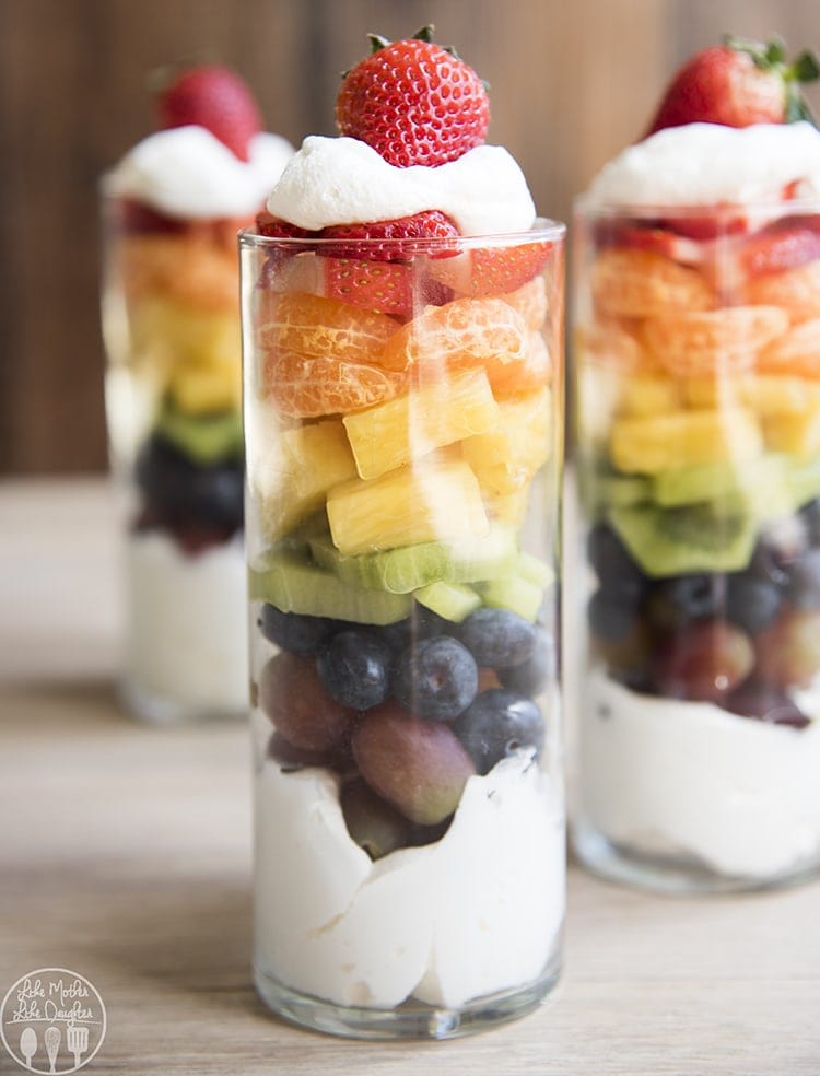 A parfait in a glass with a layer of whipped cream, and a rainbow assortment of colorful fruit.