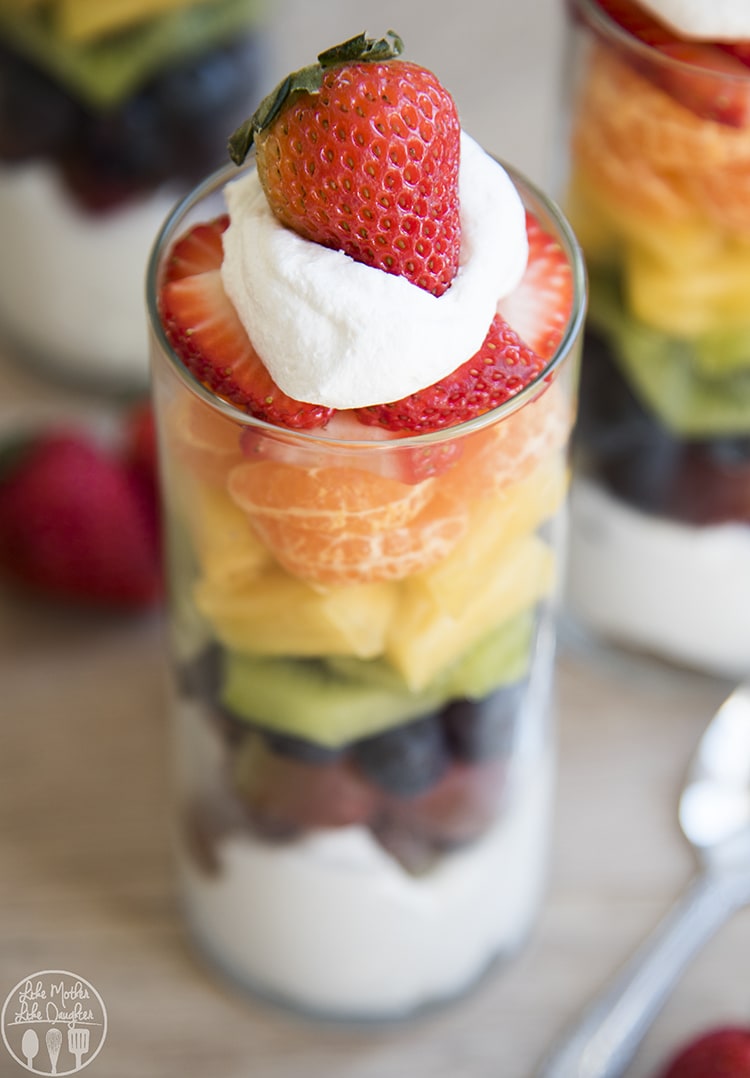 A fruit parfait with all colors of the rainbow, and whipped cream on top.