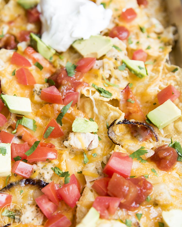Sheet Pan Nachos topped with chicken, diced tomatoes, salsa, sour cream, avocado, and cilantro. 