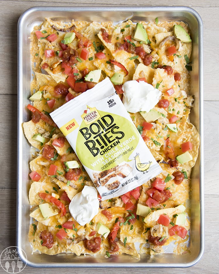 A sheet of nachos with chicken, and a Bold Bites Chicken package on the nachos.