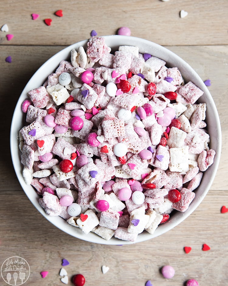 A bowl of strawberry muddy buddies with m&ms and sprinkles. 
