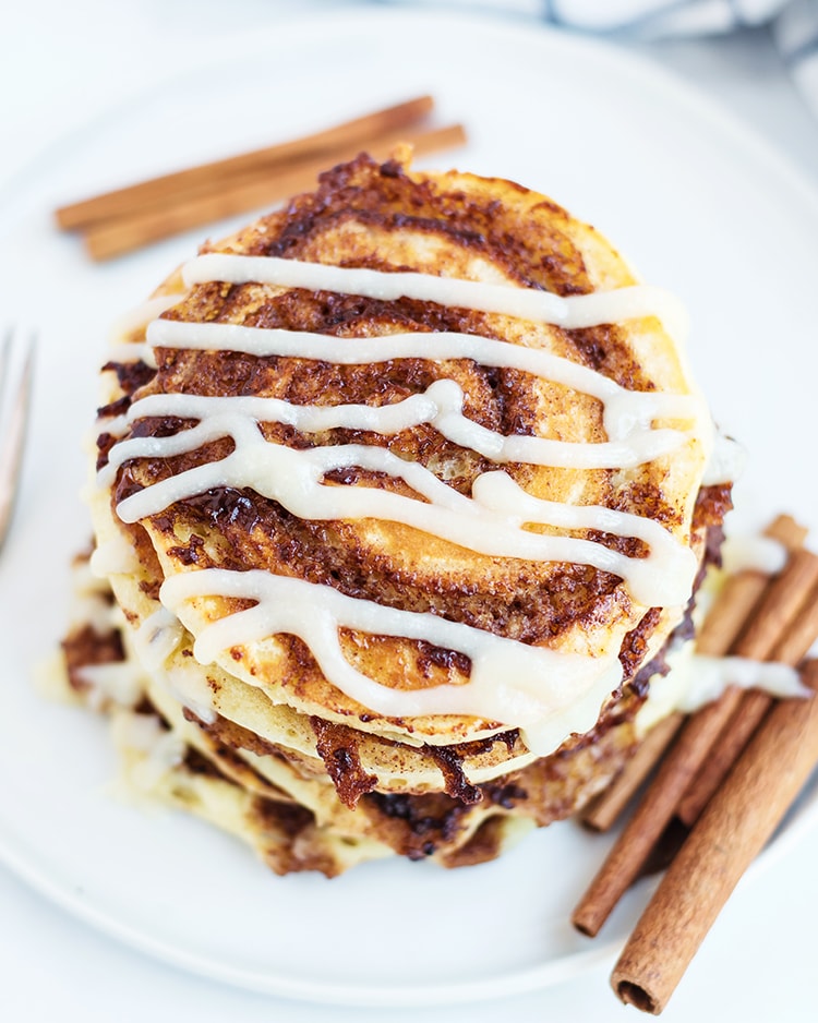 Cinnamon Roll Pancakes with a cinnamon swirl and cream cheese syrup drizzled across the top