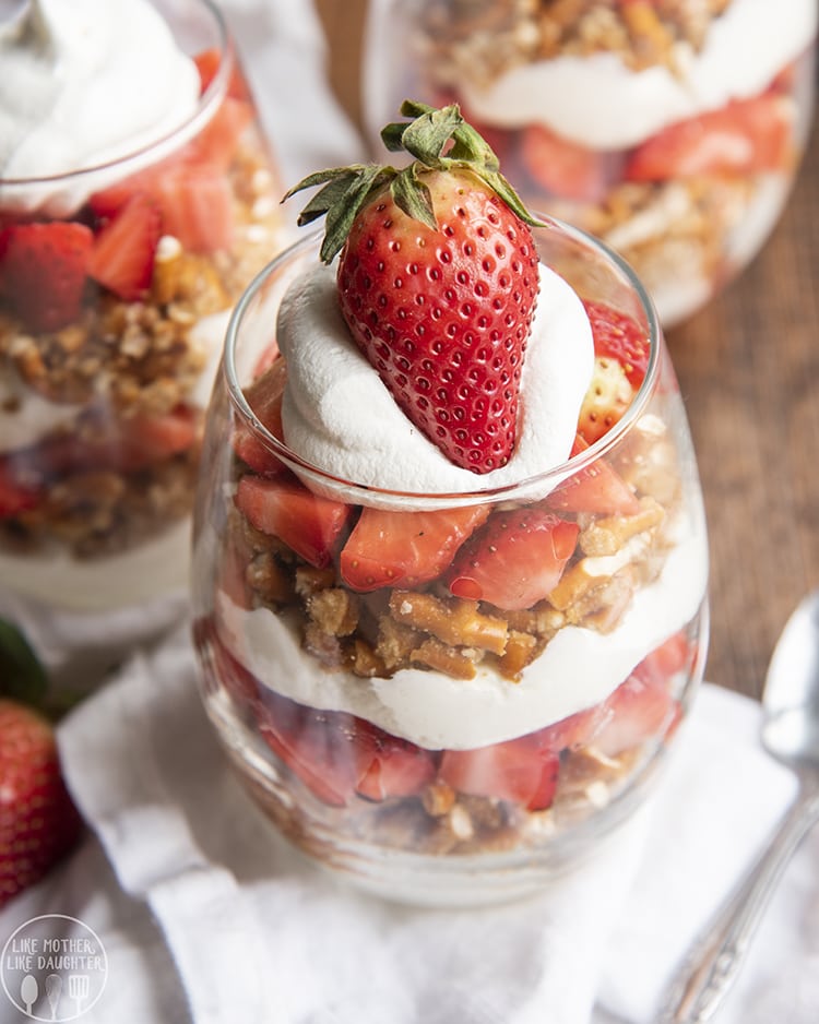 A strawberry, pretzel, and no bake cheesecake parfait in a wine glass. 