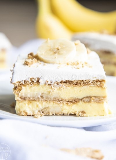 A piece of banana cream pie ice box cake showing layers of graham crackers and banana pudding.