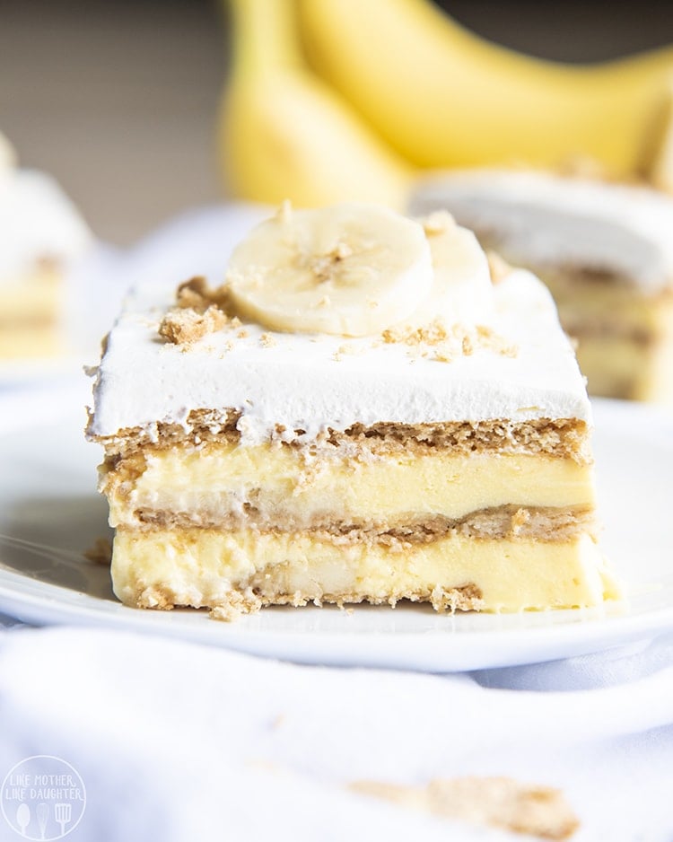 A piece of banana cream pie ice box cake showing layers of graham crackers and banana pudding.