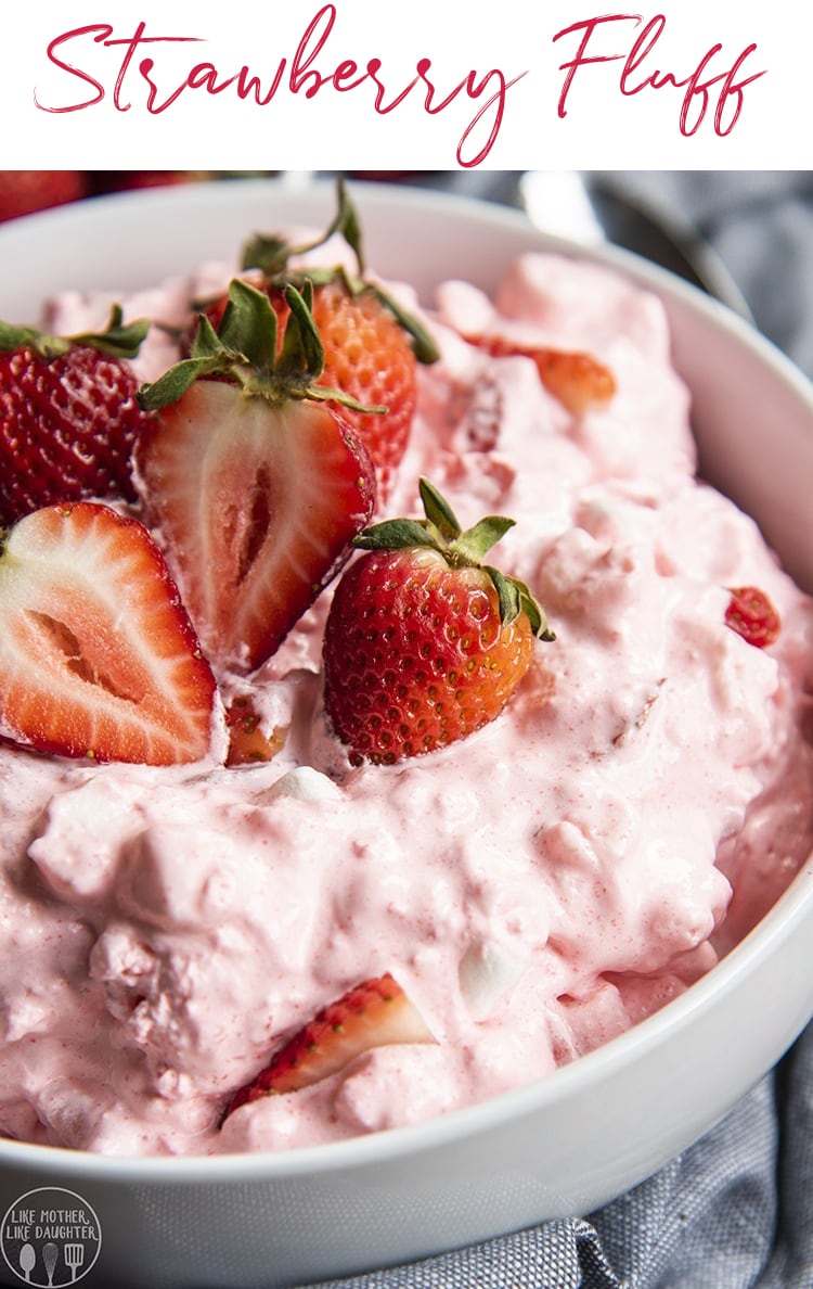 A close up of a bowl of strawberry fluff topped with fresh strawberries. 