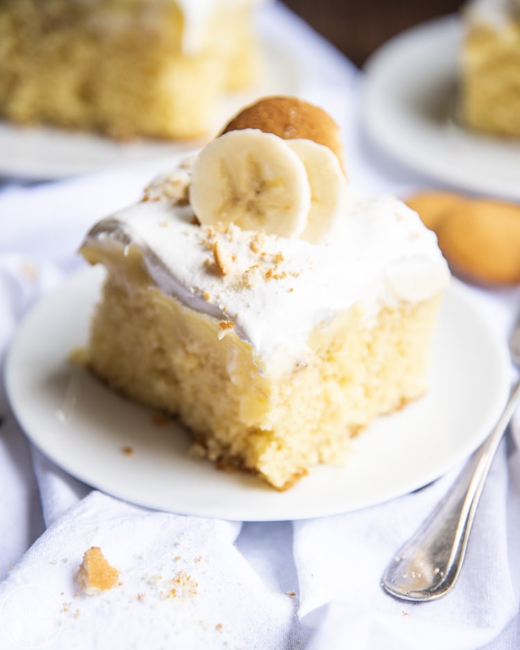 A piece of banana pudding cake with bananas and vanilla wafers on top. 